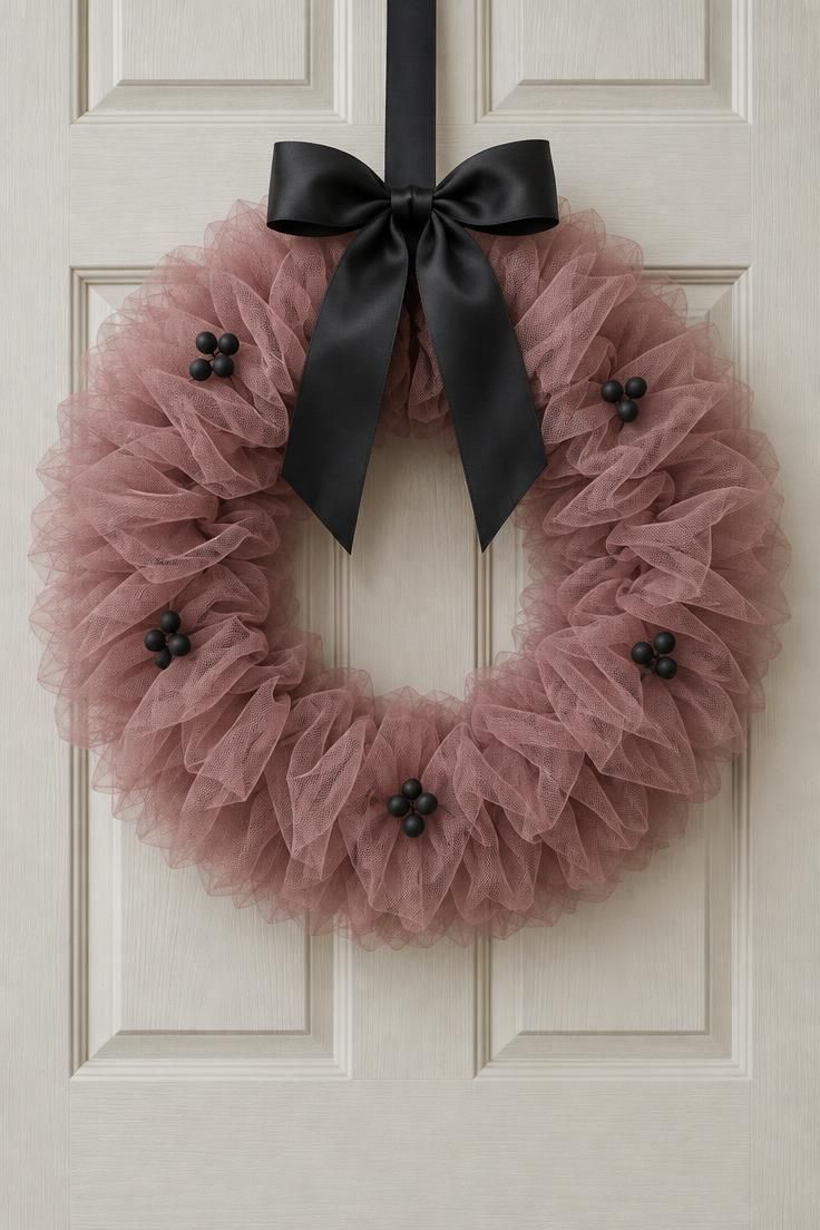 10 Dreamy Pink Halloween Decor Ideas for a Soft Spooky Look 5 A dusty rose tulle wreath with a black satin bow and small matte black berries hanging centered on a cream front door.