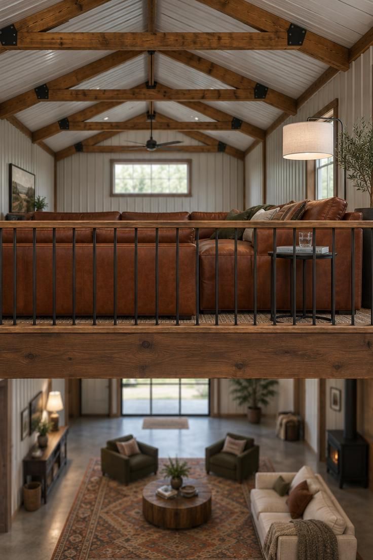 11 Warm Pole Barn Man Cave Ideas That Feel Like Home 3 Elevated mezzanine inside a pole barn with a cognac leather sectional against a simple black guardrail, a floor lamp and small side table, and exposed barn trusses visible overhead.