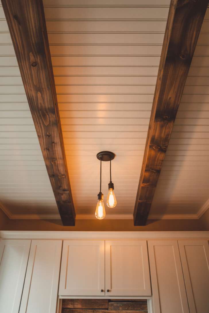 White beadboard ceiling with dark walnut exposed wood beams and black iron Edison bulb light fixture