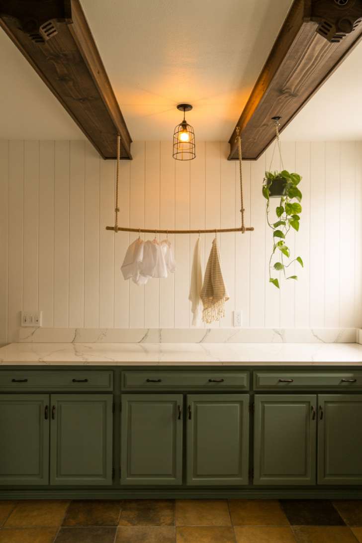 13 Gorgeous Rustic Laundry Room Ideas That Feel Like Home 6 Dark stained ceiling beams with hanging drying rack and trailing plant in a rustic laundry room