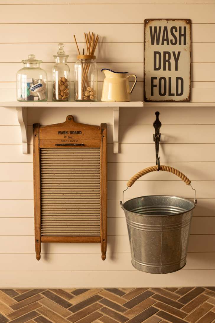 13 Gorgeous Rustic Laundry Room Ideas That Feel Like Home 9 Vintage washboard, glass apothecary jars, and enamelware pitcher styled on a white shiplap wall in a rustic laundry room