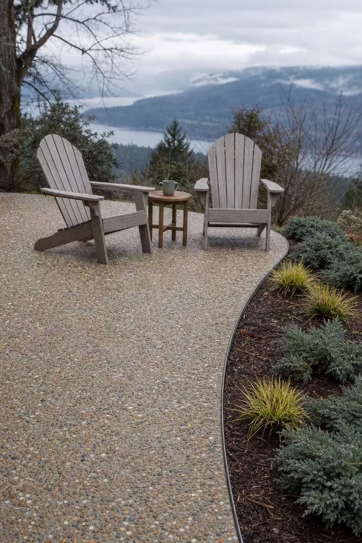 Exposed-aggregate concrete patio with steel edging and Adirondack chairs under cool overcast morning light