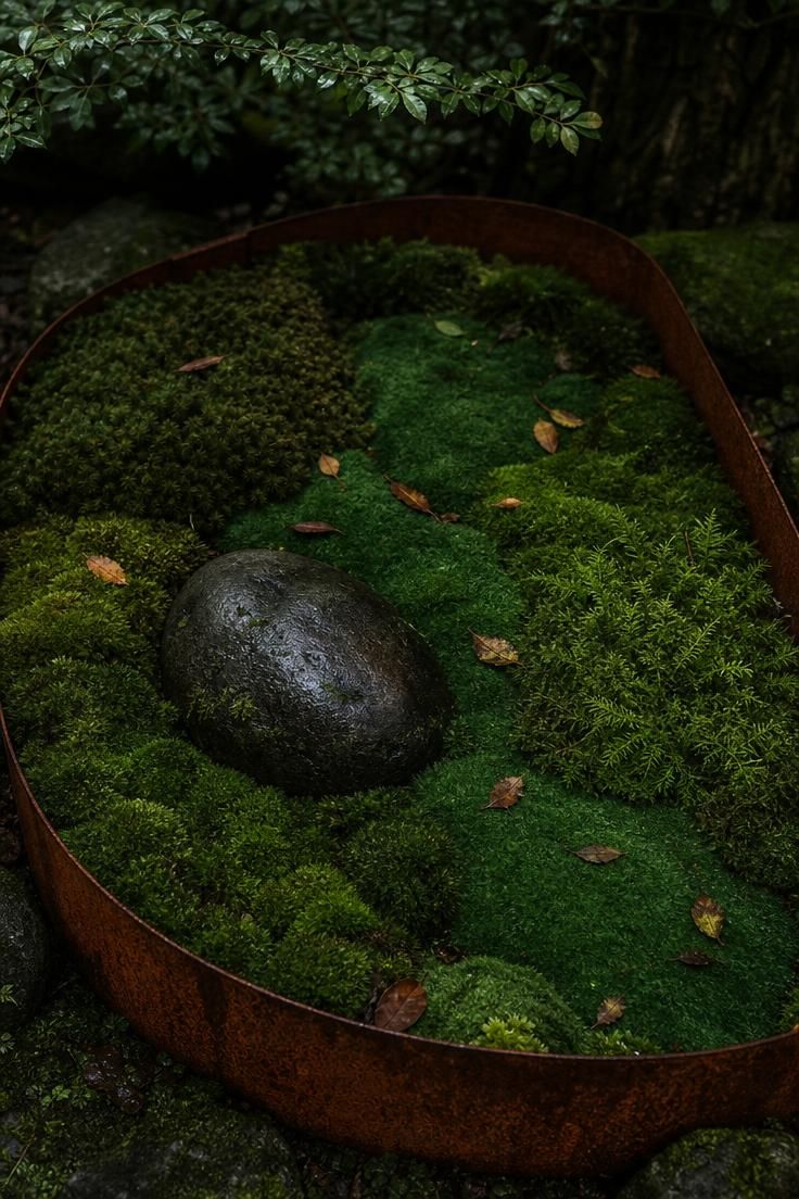 15 Fresh Small Backyard Landscaping Ideas to Try Now 7 A pocket moss garden enclosed by Cor-Ten steel edging with a single river stone in moody low light