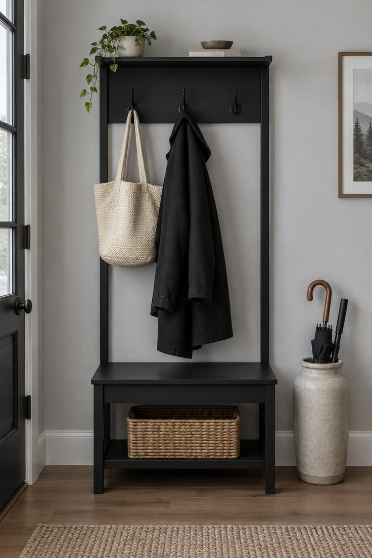 13 Cozy Small Entryway Ideas That Make Coming Home Calm 8 A matte black hall tree with three hooks, a small built-in bench, a cream woven tote hanging from one hook, and a tall ceramic umbrella jar beside it.