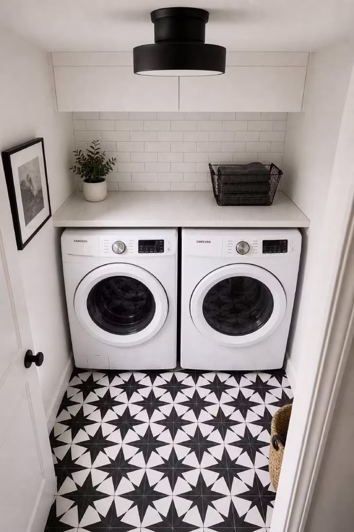 Overhead view of black and white geometric encaustic-look floor tile in a small laundry room with white subway backsplash