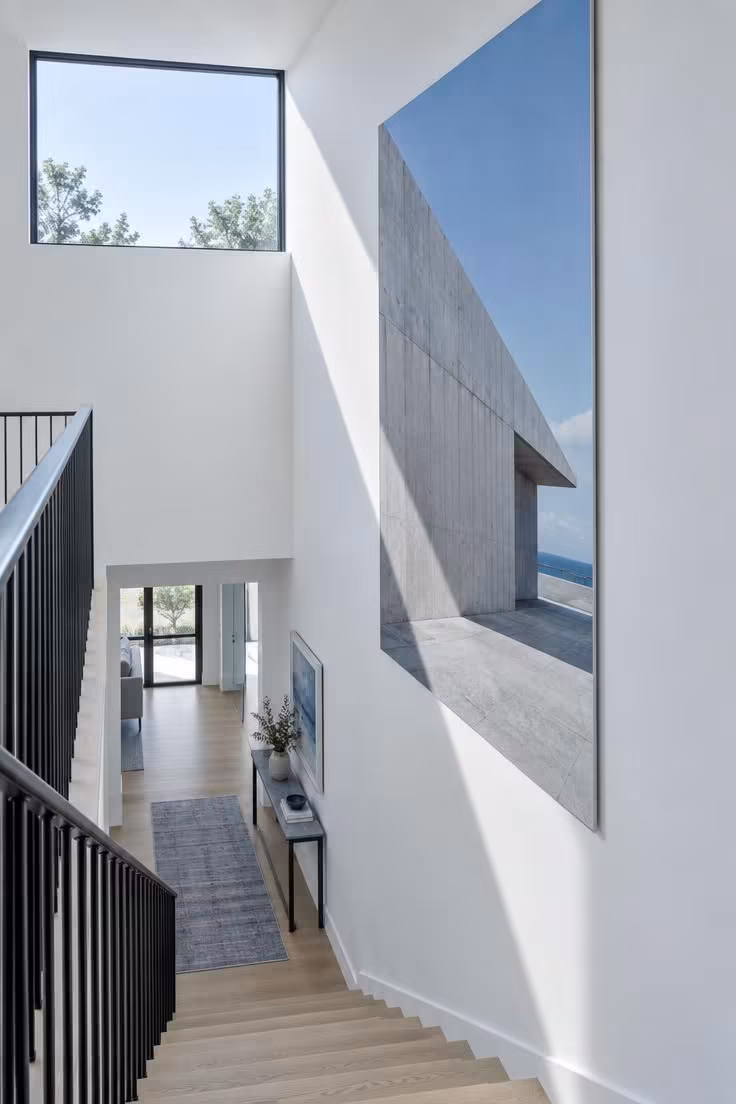 17 Cozy Stairs and Hallway Ideas You'll Want to Steal 3 An oversized architectural print filling a tall stairwell wall, viewed from the landing under cool midday light.