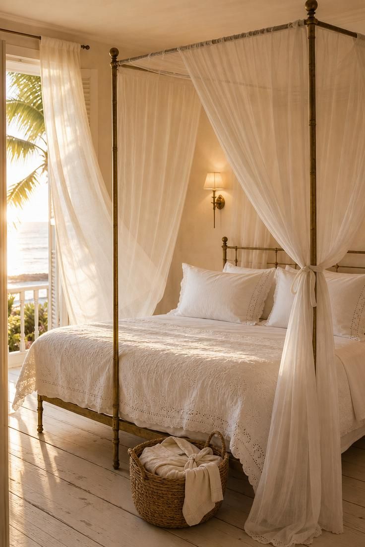 10 Breezy Summer House Bedroom Ideas For Slow Mornings 7 A white mosquito net canopy draped over a slim brass four-poster bed in warm afternoon light.