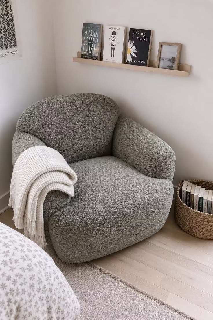 11 Cozy Teen Reading Nook Ideas to Love and Unwind 5 Sage bouclé armchair in a bedroom corner with a woven seagrass basket of books and a floating birch ledge shelf above