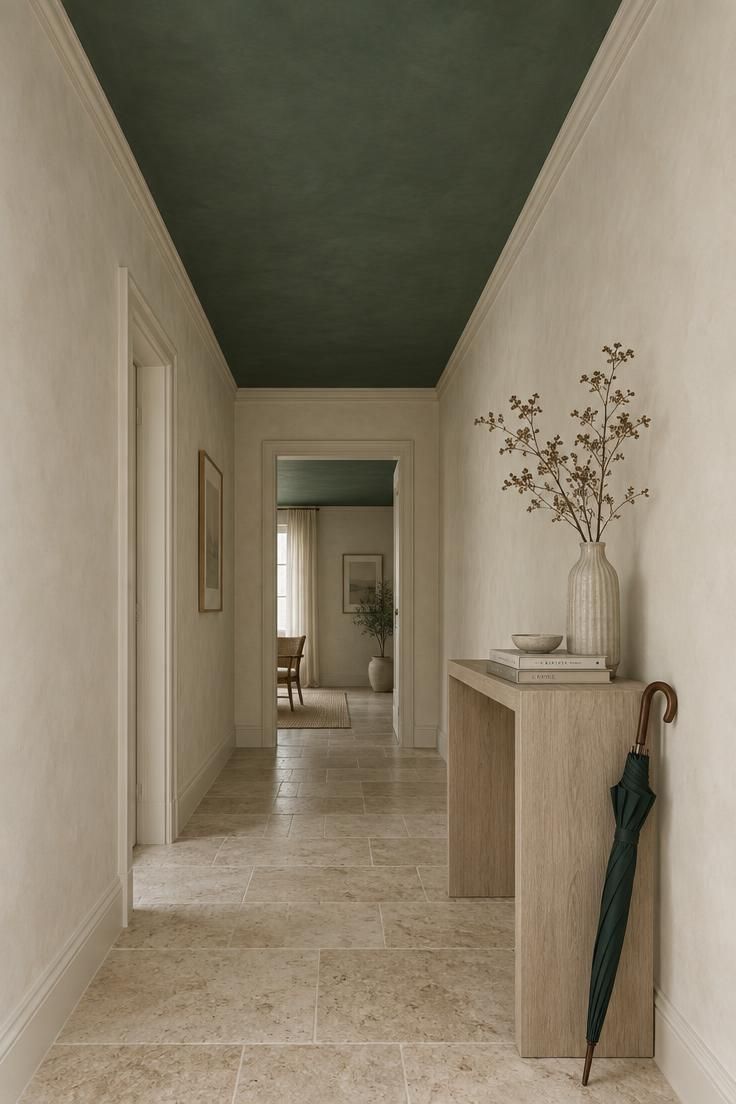 11 Warm Two Tone Hallway Ideas for Small Entryways 6 Low upward view along a hallway with a deep muted green ceiling above pale plaster walls, diffused north light, travertine floor, and a bleached oak console.