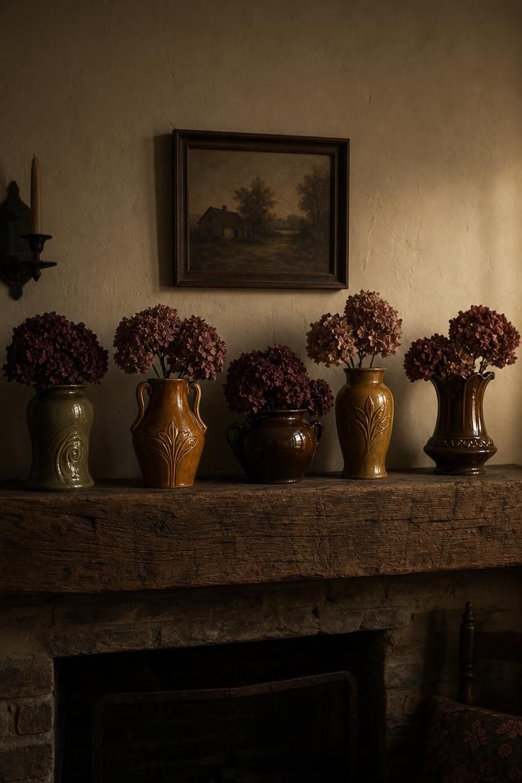 15 Vintage Fall Decor Ideas With Old-World Autumn Charm 6 Five pieces of McCoy pottery in olive, mustard, and brown glazes lined up on a rough-hewn mantel, each holding dried hydrangeas in burgundy and faded rose.