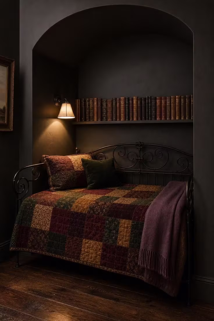 11 Charming Vintage Reading Nook Ideas You Will Love 6 A wrought iron daybed with a patchwork quilt in burgundy and mustard tucked into a dark alcove with a single wall sconce