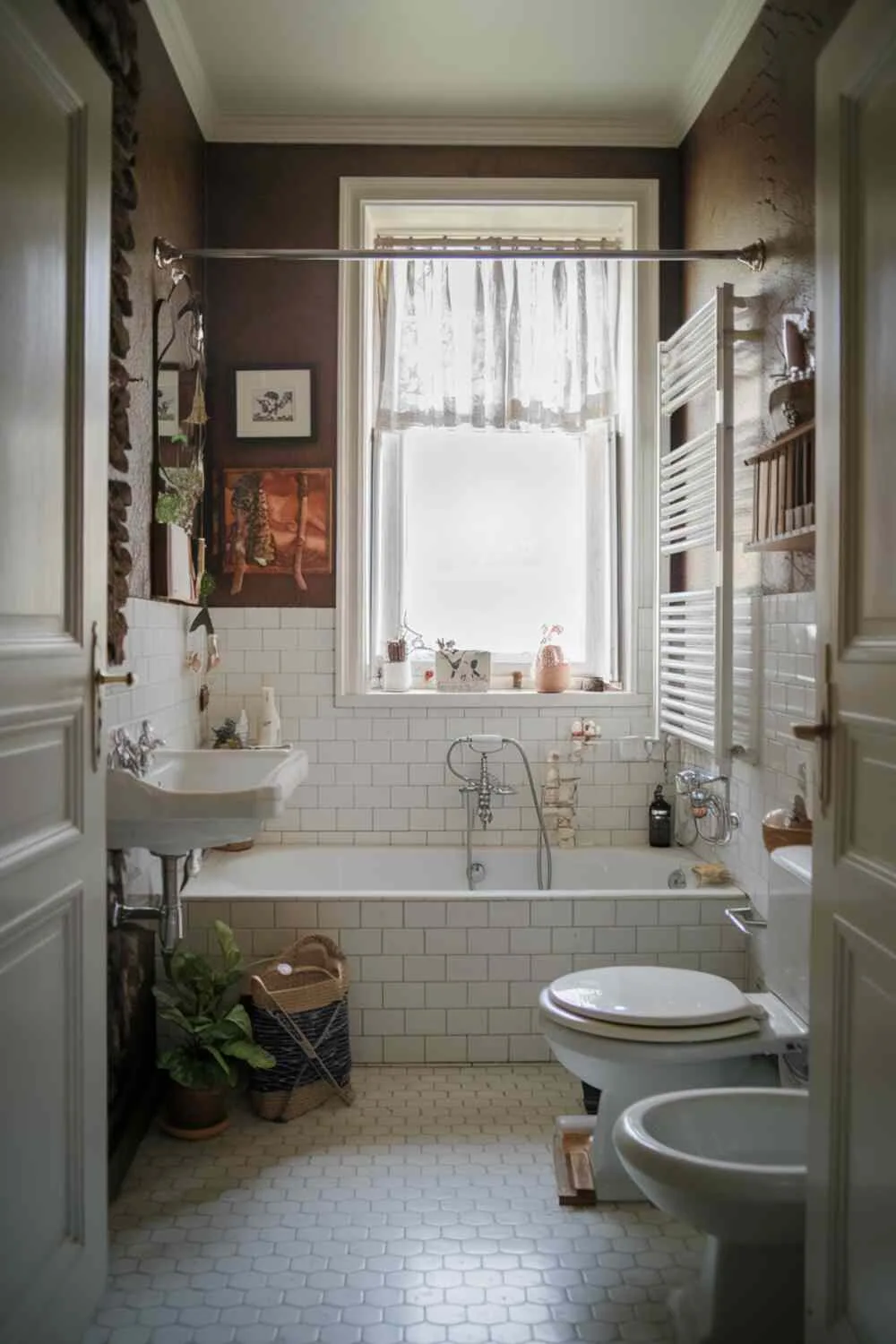 17 White Bathroom Ideas for a Fresh, Stylish Space 16 Cozy bathroom with white walls, bathtub, sink, toilet, small plant near bathtub, white tile floor, and window with curtain