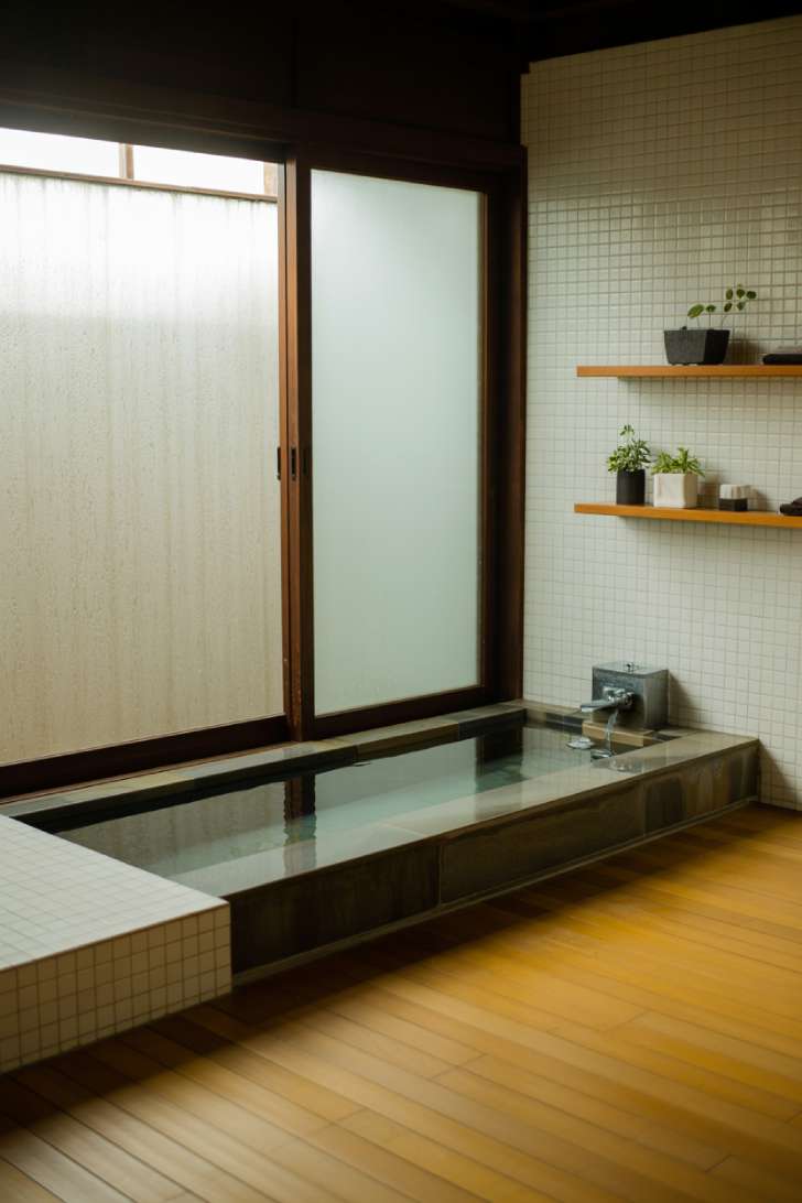 Modern Japanese bathroom with rectangular dark stone soaking tub